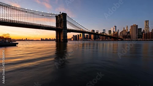 Panoramic view of the city skyline and the bridge at dusk reflects in the river. Illuminated bridge against a colorful sky creates a serene atmosphere