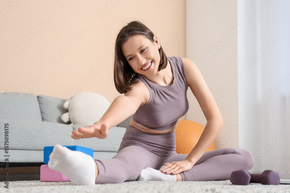 Sporty young woman stretching on carpet at home Sporty young woman stretching on carpet at home
