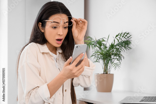 Shocked young woman using m...