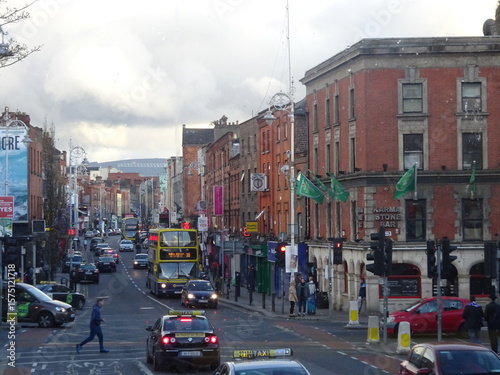 Red brick buildings and iconic Dublin buses on a lively main street with green flags