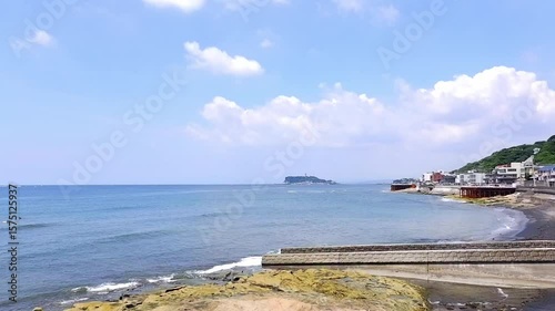 サーファーが波と戯れる夏真っ盛りの湘南・鎌倉の海と、美しい江ノ島の風景で、夏休みのイメージ
