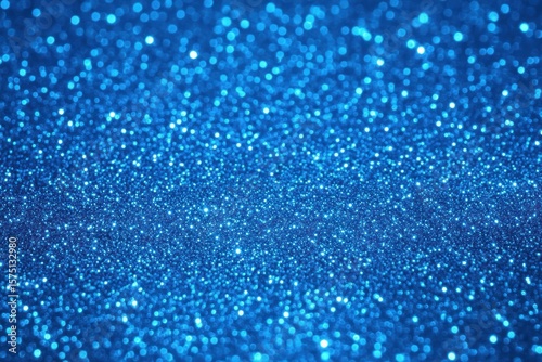 Close-up view of shimmering blue glitter creating a sparkling textured surface with blurred light reflections in the background