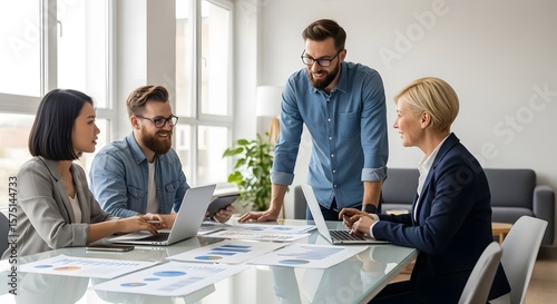 Four business professionals in a meeting discussing documents and laptops