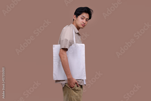 Asian Man Using Reusable White Linen Eco Canvas Tote Bag Against Blank Background for Mockup