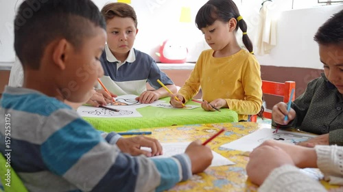Preschool children sitting at a table coloring with their teacher. Kindergarten art activity encourages creativity, fine motor skills, and learning through play