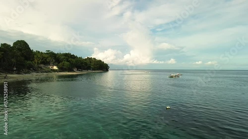 Wallpaper Mural Smooth aerial flight showcasing Beach Ni Kapitan's tropical coastline, lush greenery, calm clear waters, and anchored boats near Pangubatan, Samal Island. Torontodigital.ca