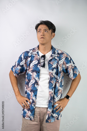 Photos Young asian man wearing blue summer shirt is thinking and making suspicion face expression gesture, isolated over white background