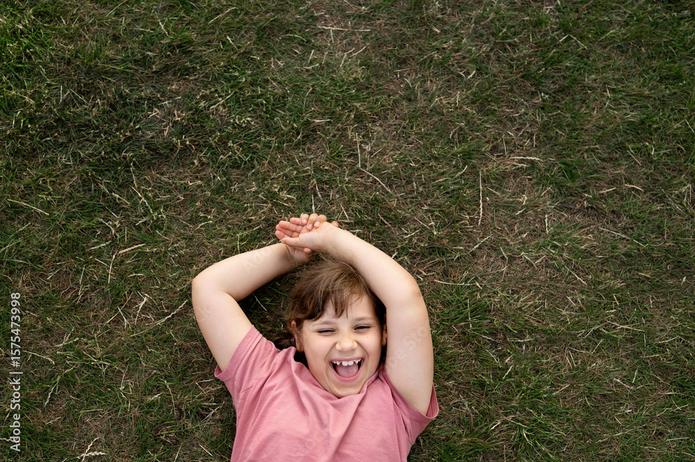 Laughing child girl with arms crossed behind head lying on the grass. Laughing child girl with arms crossed behind head lying on the grass.