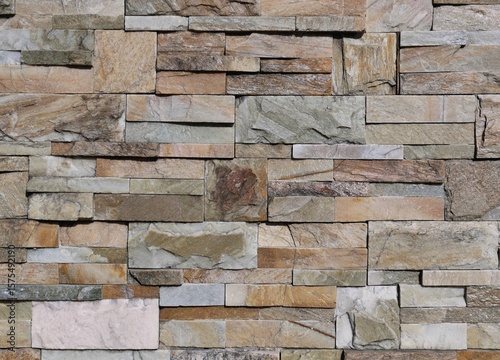 Multicolored external wall made of different types of rocks with different shapes. Background and texture.