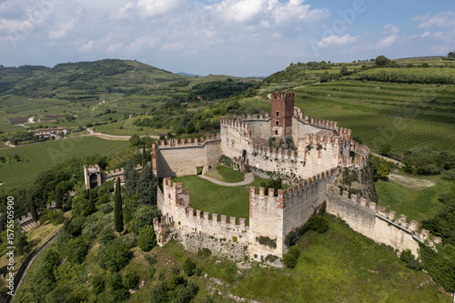 Aerial view of the ancient Castello Scaligero fortress standing proudly amid the vibrant green hills, a timeless sentinel overlooking the landscape, Castello Scaligero, Veneto, Italy.