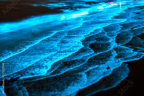 Bioluminescent waves shimmer along the shoreline in New South Wales, Australia, creating a surreal glow in the night.