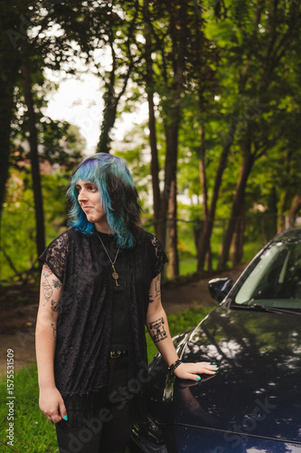 Transwoman with dyed hair standing outdoors by a car