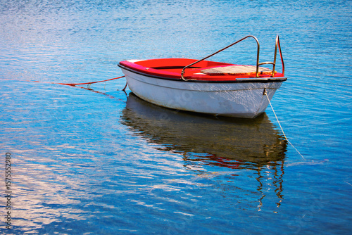 Wooden boat anchored in the calm water, displays a serene and tranquil atmosphere