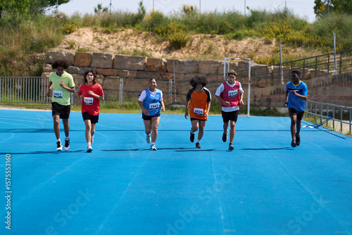 Six young athletes running on blue track