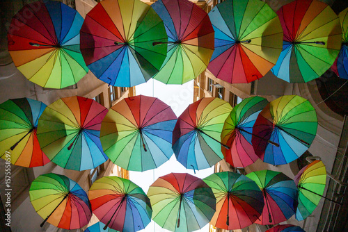 Colorful umbrellas decorate narrow alleyway in vibrant display during a sunny day in a lively urban area