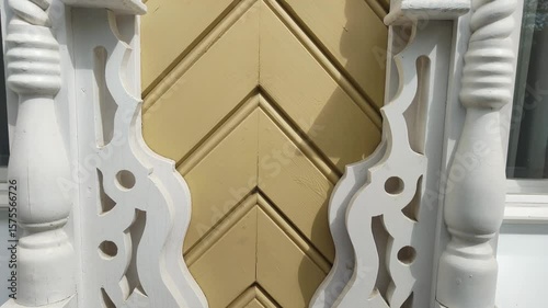 Carved decoration of facade of building. Close-up of sawn thread. White trim panels openwork carving on windows of yellow house. Fretwork