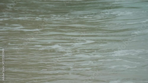 Closeup of sea waves crashing on beach sand.