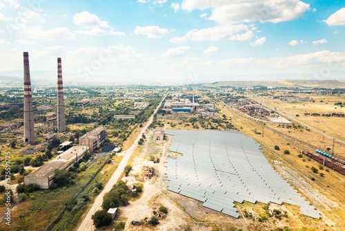 Foto Aerial fly over view of solar power plant or farm next to abandoned industrial c
