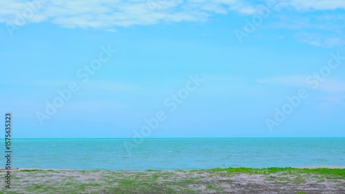 Sandy beach with beautiful grass along the vast tropical beach of Songkhla province. Blue sea and sky.