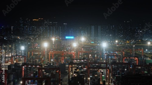 Wallpaper Mural Cargo Cranes Loading And Unloading Containers On Trucks In A Busy Illuminated Container Terminal At Night With The Hong Kong Skyline In The Background. International Trade, Logistics Hub Torontodigital.ca