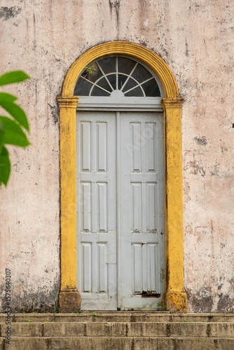 Single gray paneled door stands beneath a half-moon transom window.