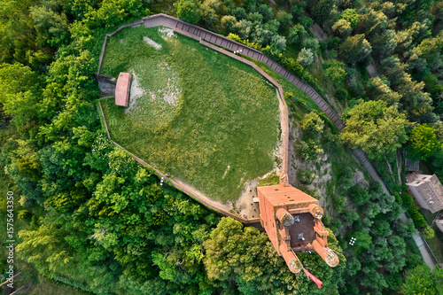Aerial view of a medieval fortress of Rocca di Federico II with its red brick tower surrounded by lush green forest, San Miniato, Tuscany, Italy.