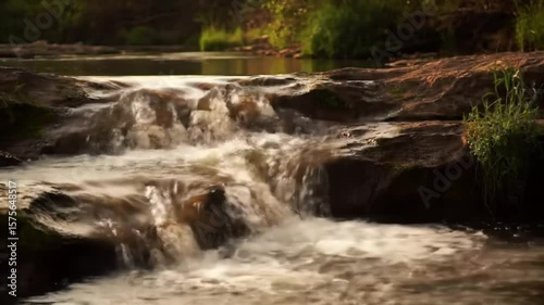 Peaceful Cascade Water Flows Over Rocks Through Lush Greenery