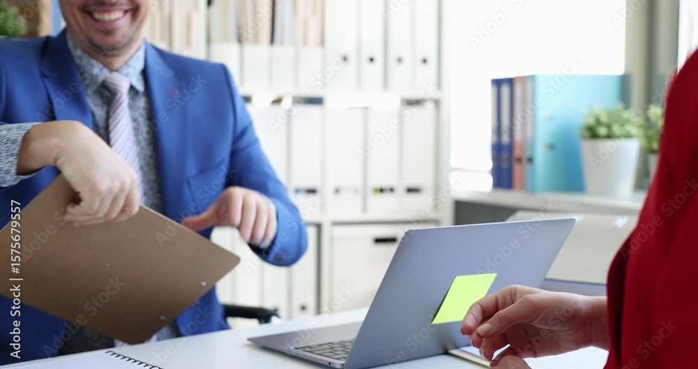 Woman in red dress handshakes with man and signs document presented on clipboard. Act of agreement at desk in modern business setting slow motion