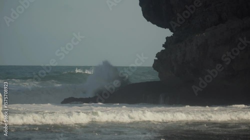 Long shot of ocean waves crashing on sea rocks.