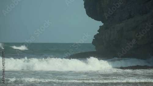 Long shot of ocean waves crashing on sea rocks in 120 fps slow motion.