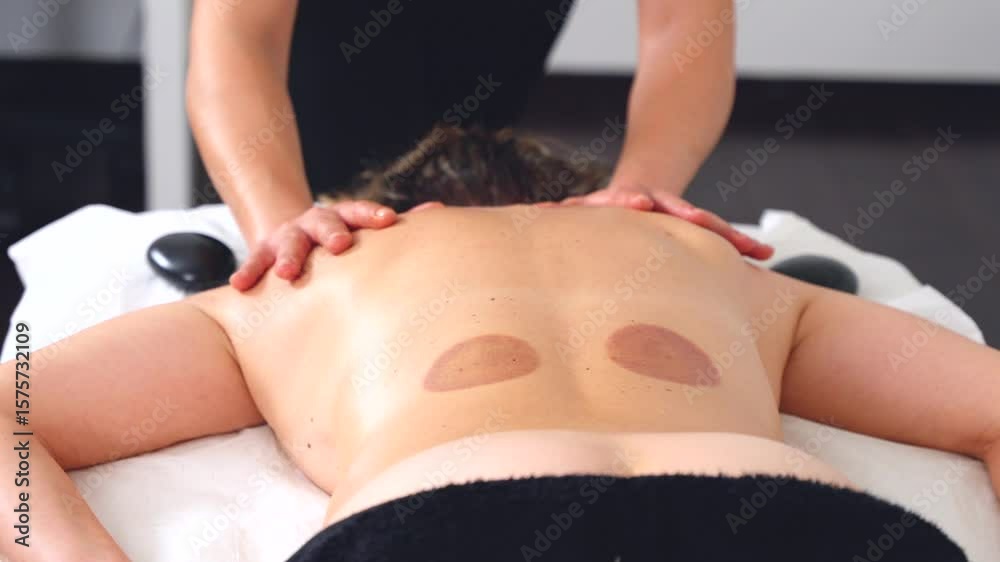 Close-up Professional massage therapist performing a back massage in a clean,bright spa room.Client lying face down on table. Perfect for themes of wellness, therapy,relaxation, and body care services