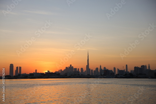 Photography Golden sunset over Dubai skyline with silhouettes of palm trees and wooden pier