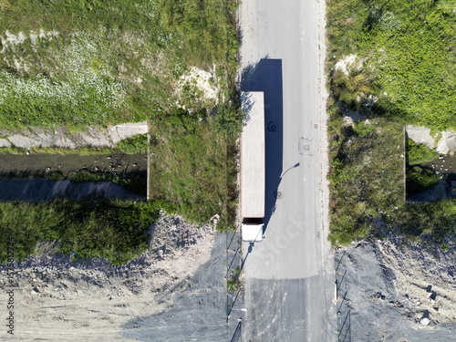 Aerial view of a truck traversing a narrow bridge, stark against the verdant landscape, the scene bathed in the diffuse light of midday, Istanbul, Ä°stanbul, TÃ¼rkiye.