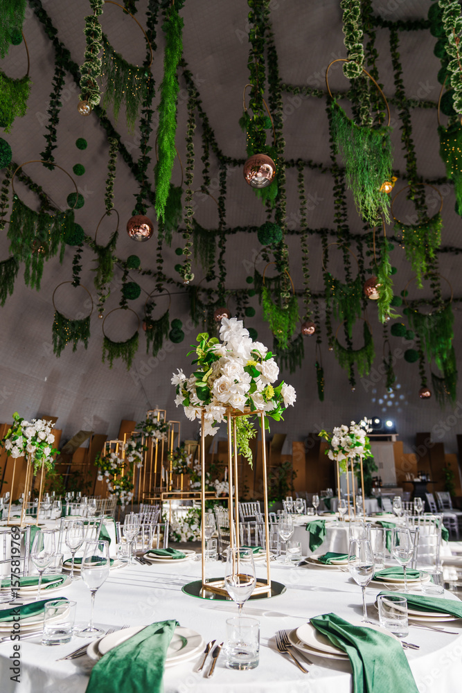 Obraz premium flower arrangements, empty glasses, plates with green napkins on a table.