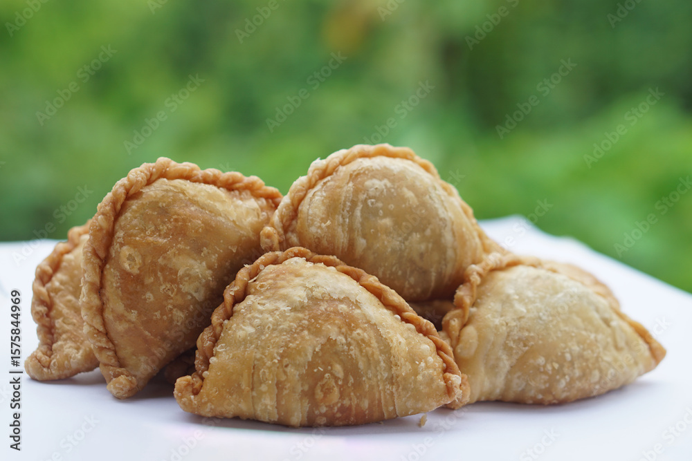 Fototapeta premium Homemade crispy golden brown curry puffs or karipap in Thai. Concept, traditional snack. A beloved savory pastry filled with spiced fillings, perfect for tea time or festive gatherings. 