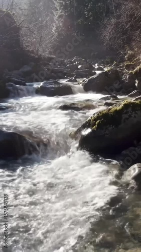 A rushing mountain stream flows over rocks in a misty forest.