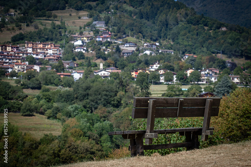 Wooden Bench Overlooking Scenic Village with Rolling Hills and Forested Backdrop