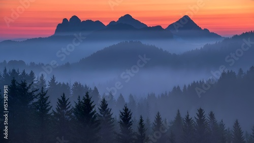 Scenic Mountain Vista at Dawn: A breathtaking mountain range silhouette rises against a vibrant, colorful dawn sky, enveloped in a mystical morning fog.