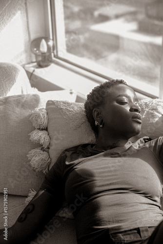 Portrait of a young Black queer woman looking out the window