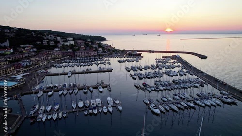 Sunset on an Italian marina with a clear sky, colorful sun, boats in the marina