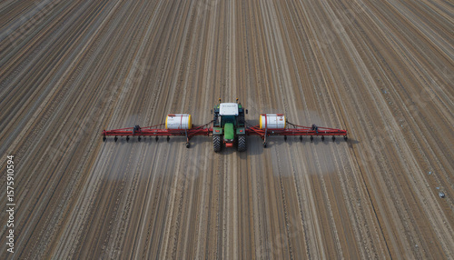 Aerial view of a tractor seeding a vast, precisely tilled field. Represents modern agriculture, efficiency, and large-scale food production