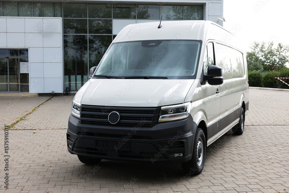 One white minibus parked on paved road outdoors One white minibus parked on paved road outdoors