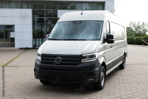 One white minibus parked on paved road outdoors