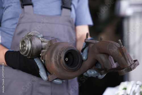 Auto part. Professional mechanic with turbocharger indoors, closeup