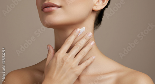 Close-up of a woman's neck and hands applying skincare product.