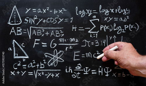 Mano escribiendo operaciones y formulas de física cuántica y matemáticas con una tiza en la pizarra