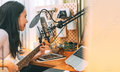 Fotografie Asian woman singer on microphone playing electric guitar using technology live s