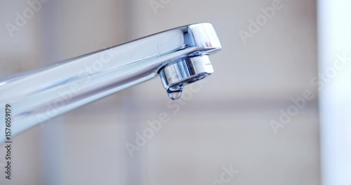 Dripping tap with water droplets inside apartment bathroom. Macro, close up, looking up shot, shallow depth of field, real time, no people