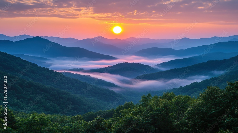 Obraz premium A vibrant sunrise illuminates layered mist-covered mountains with lush green forests under a colorful sky.