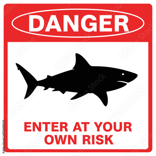 A red and white danger sign featuring a shark silhouette and the warning "Enter at Your Own Risk".